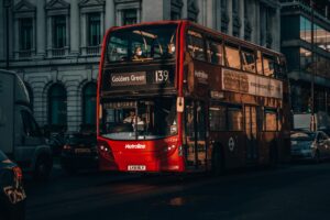 Capture of a red double-decker bus on a street in London, showcasing city transport and architecture.